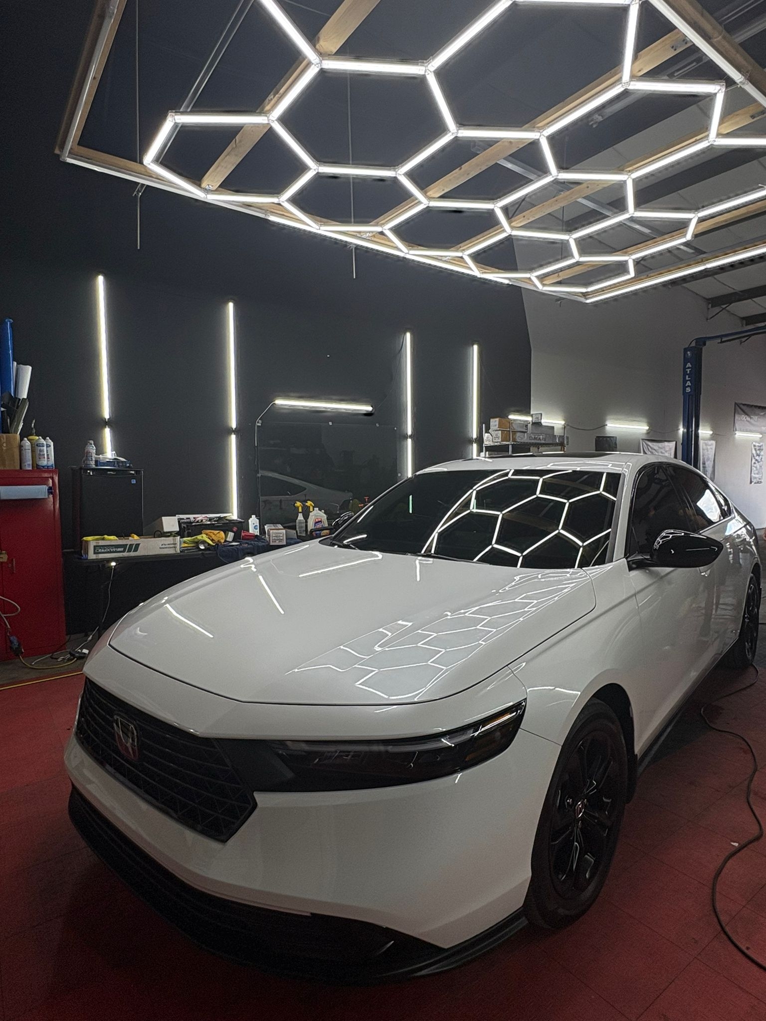 White Honda Integra under hexagonal light fixture.